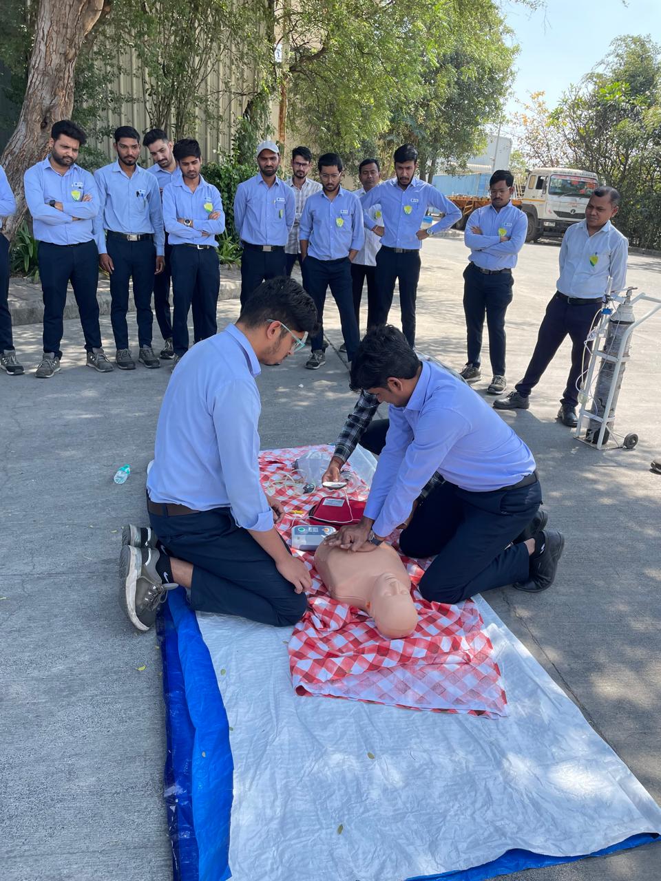 CPR practice on a mannequin with an AED trainer at an industrial site