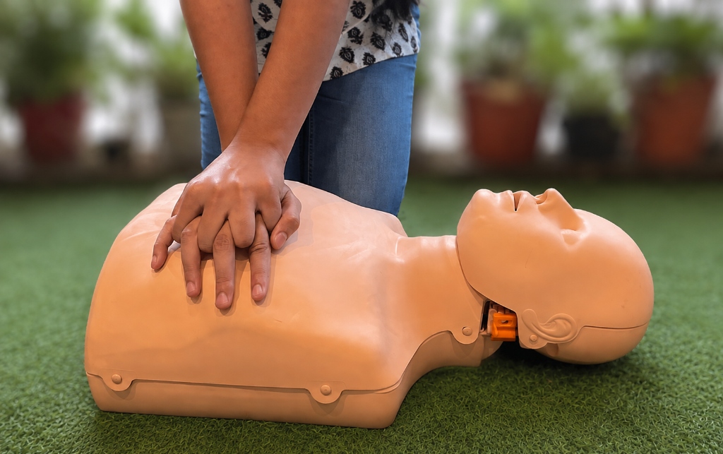 Individual performing chest compressions on a CPR mannequin